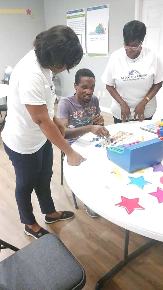 A Gregory & Friends staff member guiding a participant through a hands-on color and shape sorting activity at the center